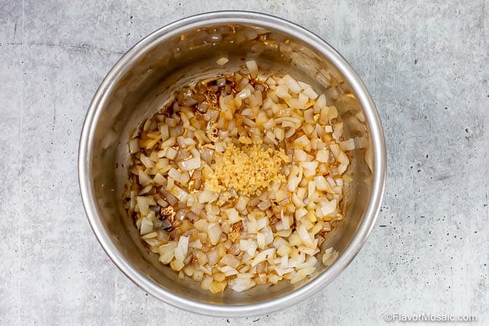 Chopped onions and minced garlic sizzling in a stainless steel pot, turning translucent and lightly browned-perfect for starting your Instant Pot Black Eyed Peas recipe.