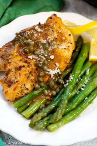 Instant Pot Chicken Piccata on white plate with asparagus and slice of lemon.