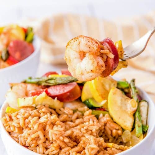 Cajun Shrimp And Sausage Sheet Pan Dinner served with Cajun Rice in a bowl.