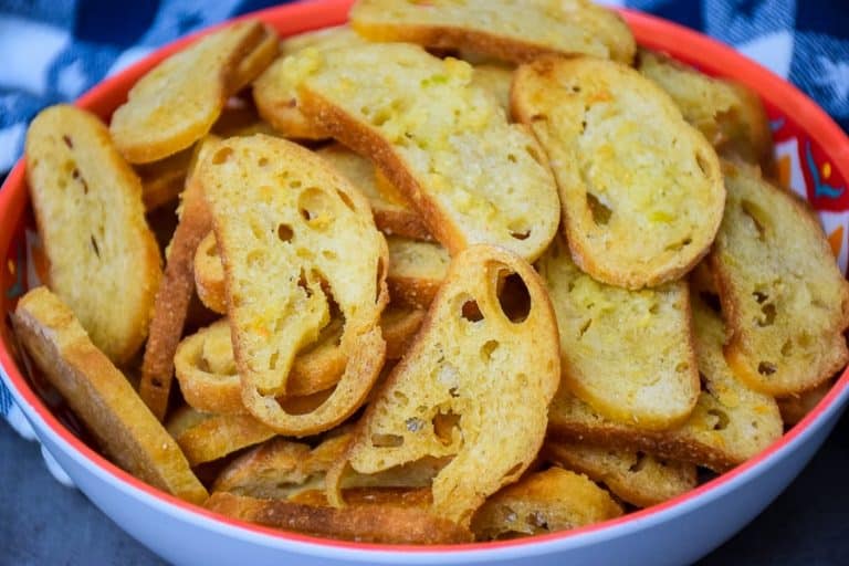 Close up photo of Buttery Garlic Bread Chips in a blue bowl with peach colored trim
