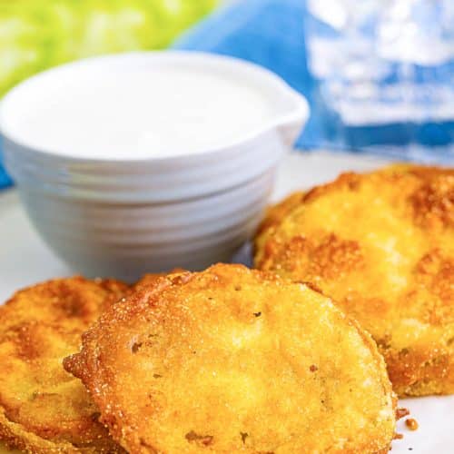 3 sliced Fried Green Tomatoes on a white plate with a small bowl of dipping sauce for fried green tomatoes.