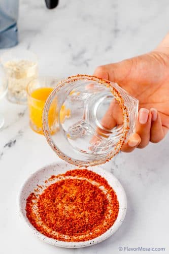Add tajin and salt on a small plate and then dip the rim of the glass in the tajin mixture.