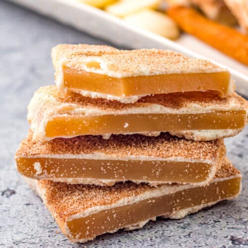 A stack of 4 Churro Toffee bars in front of a platter of more churro toffee.