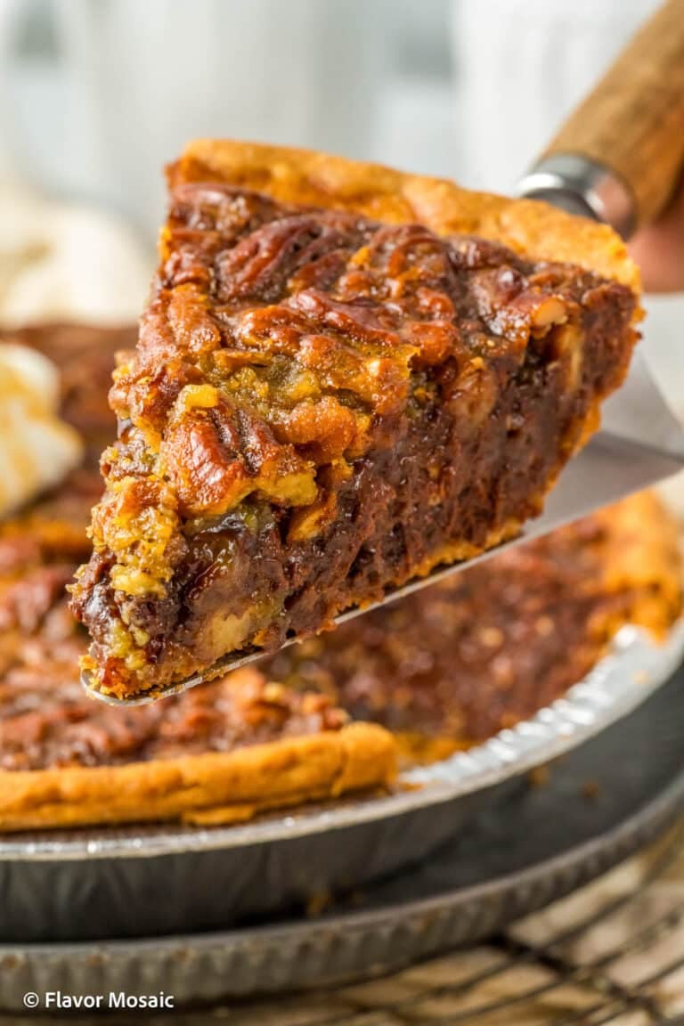 A slice of Kentucky Derby Pie (Chocolate Pecan Pie) being held over the rest of the pie plate and cooling rack.