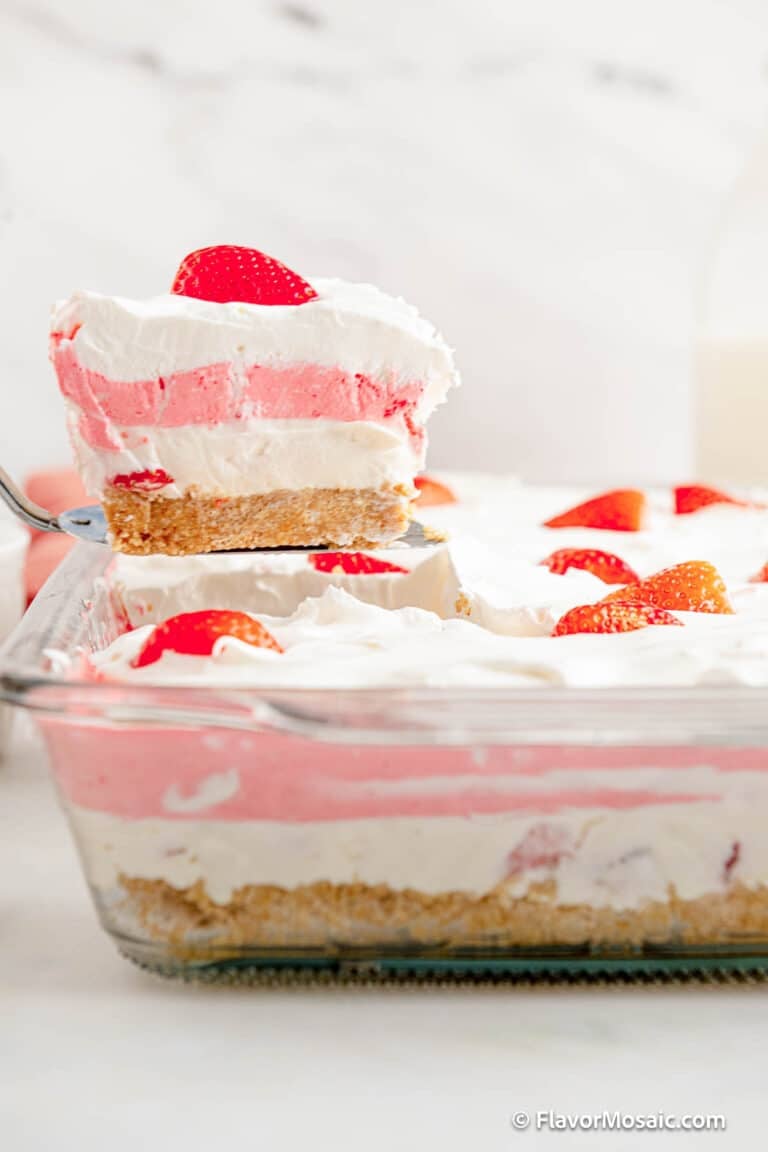 A serving of Strawberry Lasagna Dessert is held above the rest of the dessert in the pan.