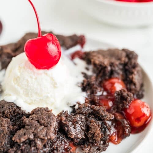 A serving of Chocolate Cherry Dump Cake with whipped cream and a cherry on top.