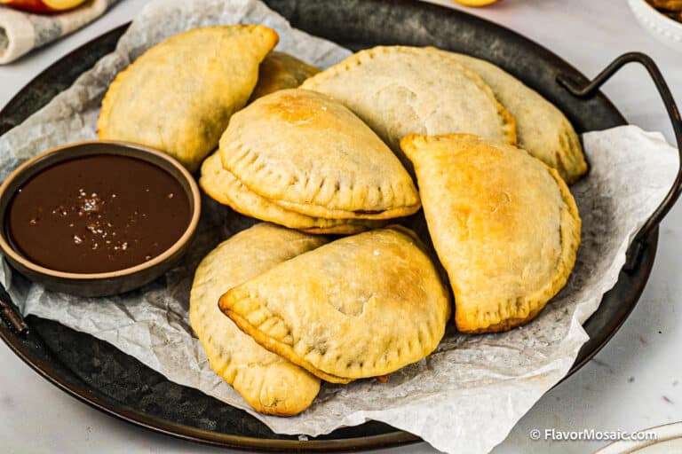 Apple empanadas on a serving tray with a small bowl of cajete (caramel.)