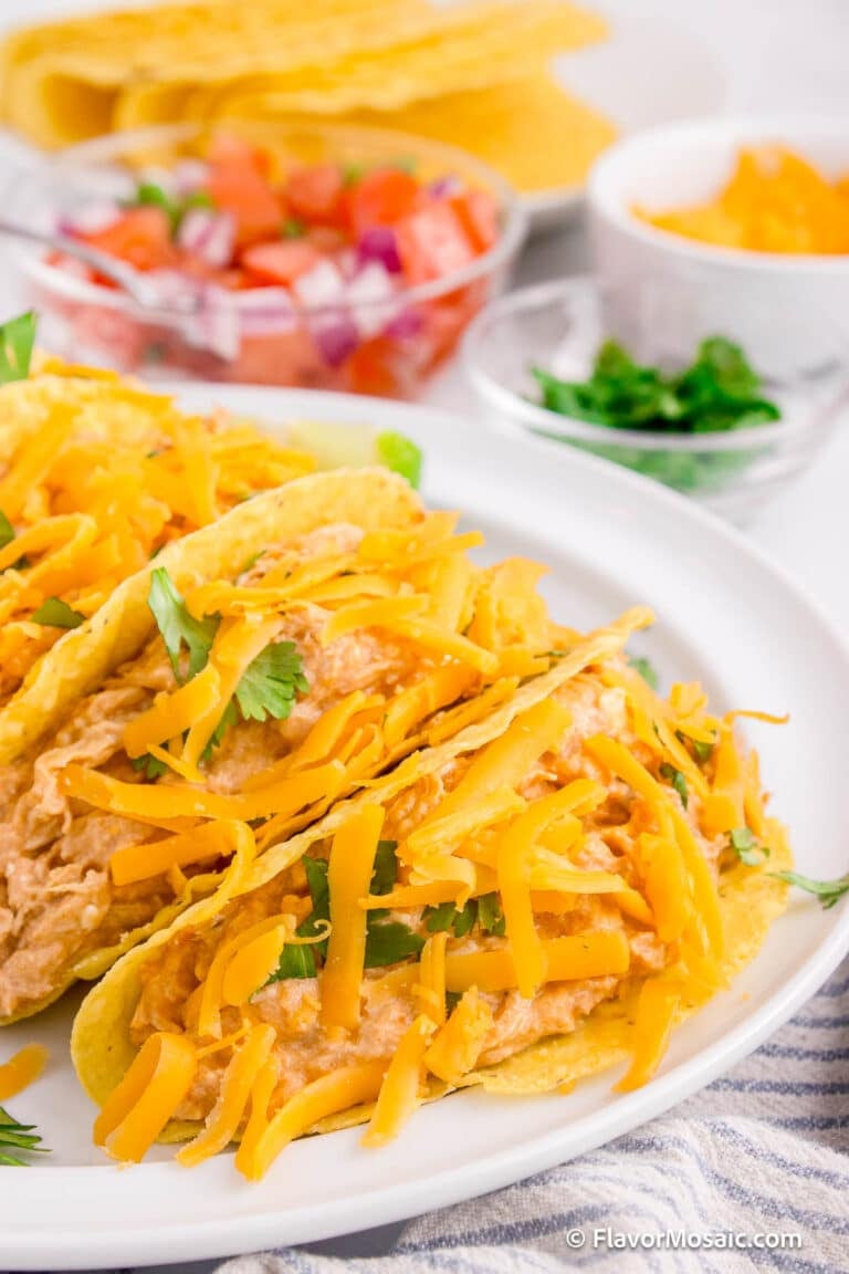 Slow Cooker Cream Cheese Salsa Chicken shown as filling inside hard taco shells.
