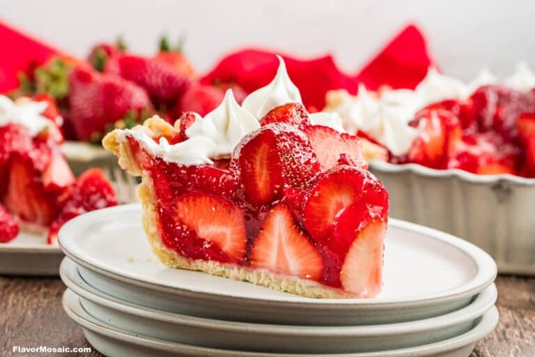 A slice of Fresh Strawberry Pie topped with whipped cream sits on a stack of white plates, with whole strawberries and the rest of Shoney's Strawberry Pie visible in the background.