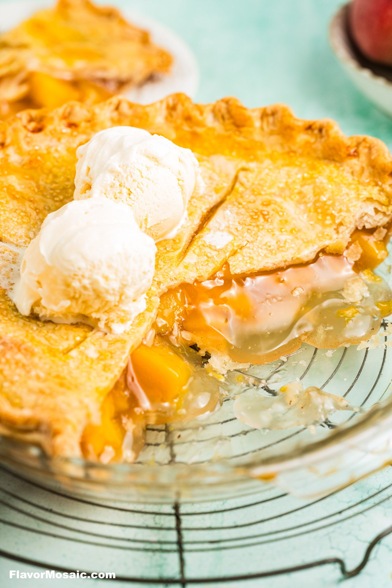 Canned Peach Pie on a cooling rack with a few slices removed so you can view the pie filling, flaky crust, and vanilla ice cream on top.
