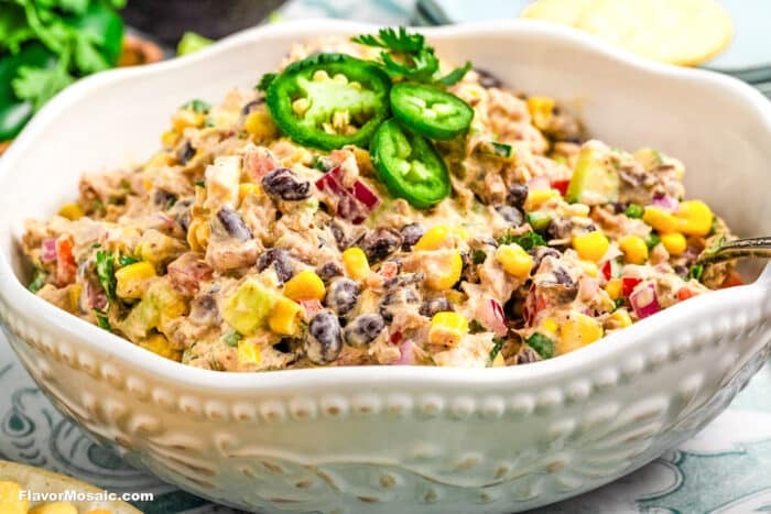A bowl of creamy Southwest salad with black beans, corn, red onion, diced avocado, and herbs, garnished with sliced jalapeño and cilantro-similar to a vibrant Mexican Tuna Salad but perfect for vegetarians.