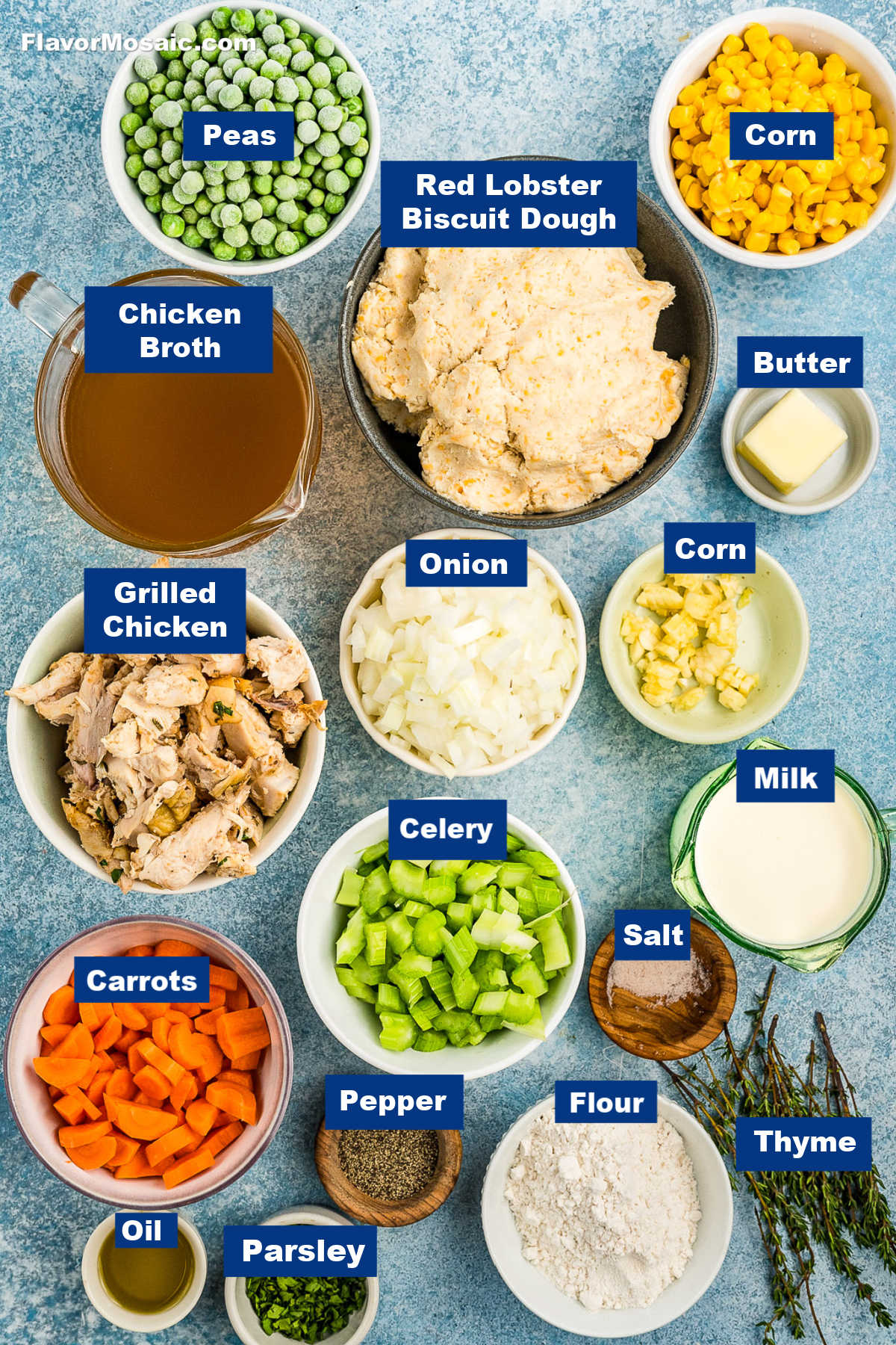 Various labeled ingredients for a Cheddar Bay Biscuit Chicken Pot Pie are arranged on a blue surface, including peas, grilled chicken, carrots, biscuit dough, onions, celery, and more-perfect for a savory Chicken Pot Pie with Cheddar Bay Biscuits.