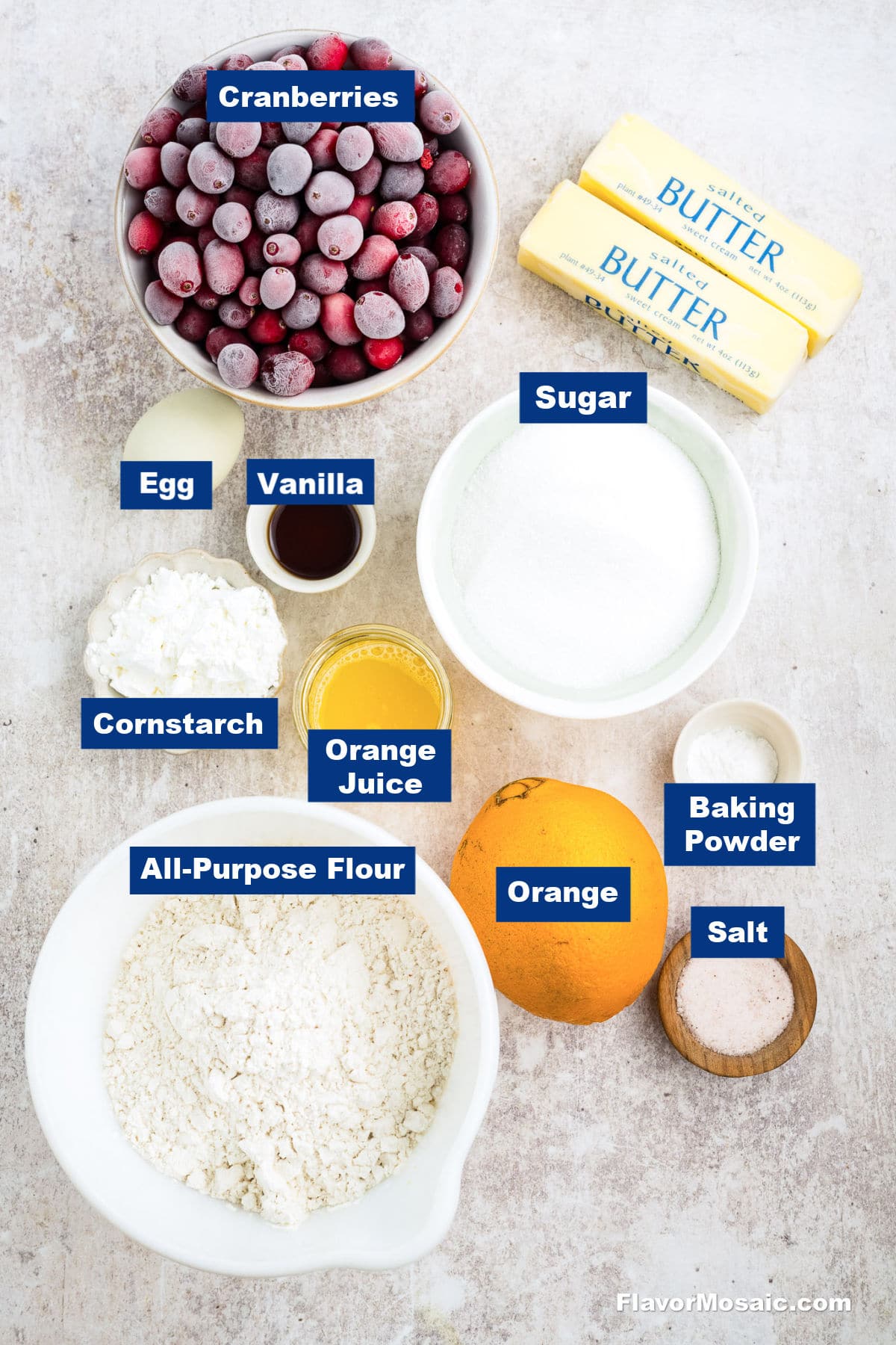 Overhead view of labeled baking ingredients for Cranberry Crumb Bars: frozen cranberries, two sticks of butter, egg, vanilla, sugar, cornstarch, orange juice, whole orange, all-purpose flour, baking powder, and salt on a light surface.