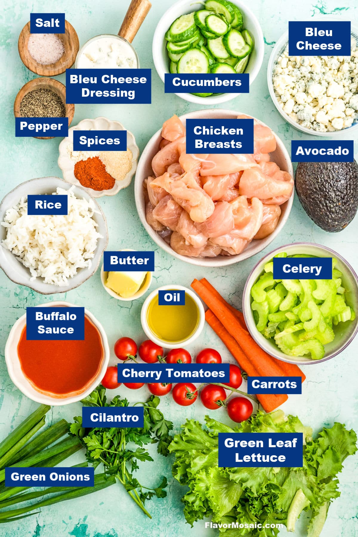 A variety of labeled ingredients on a light blue surface, including chicken breasts, rice, cucumbers, carrots, celery, avocado, bleu cheese, cherry tomatoes, green onions, cilantro, green leaf lettuce, spices, salt, pepper, butter, oil, bleu cheese dressing, and buffalo sauce.