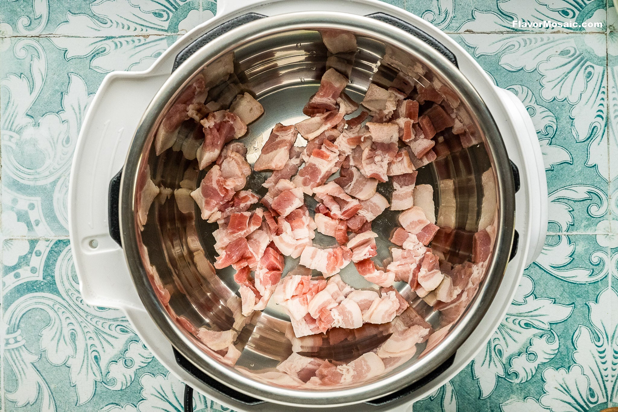 Diced raw bacon pieces in an Instant Pot on a patterned blue and white countertop, ready to be cooked for delicious Instant Pot Charro Beans (Frijoles Charros).
