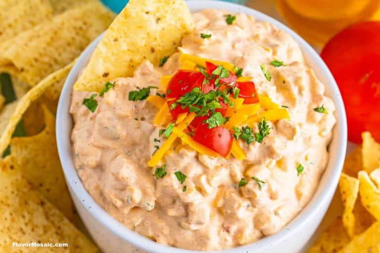 A bowl of creamy dip, inspired by classic corn recipes, topped with shredded cheese, chopped tomatoes, and parsley, surrounded by crispy tortilla chips.