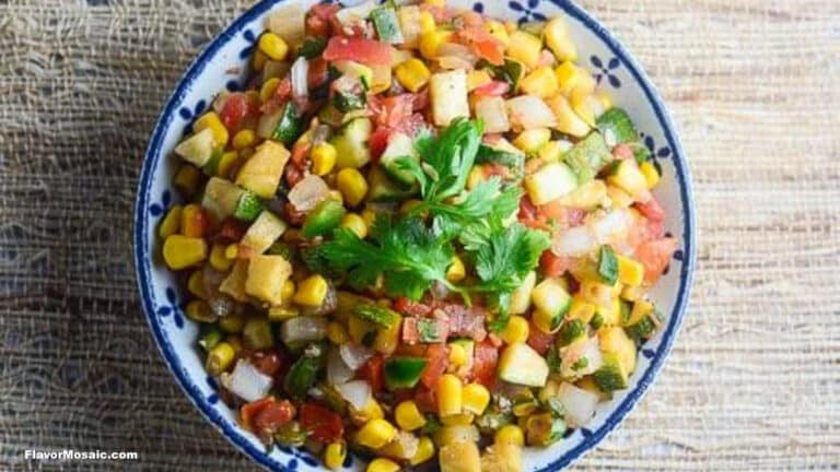 A bowl of colorful corn salsa with diced tomatoes, onions, zucchini, and cilantro on top, placed on a woven surface-a vibrant addition to your collection of corn recipes.