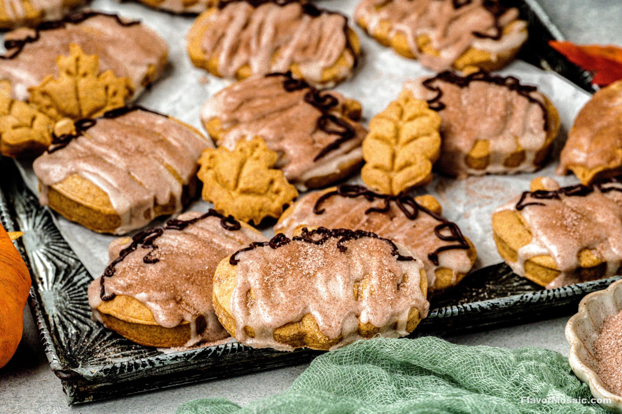 Iced Pumpkin Sugar Cookies with a Maple Glaze sitting on a cookie sheet ready to be plated to serve.